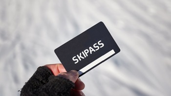 Tessera skipass in mano con neve